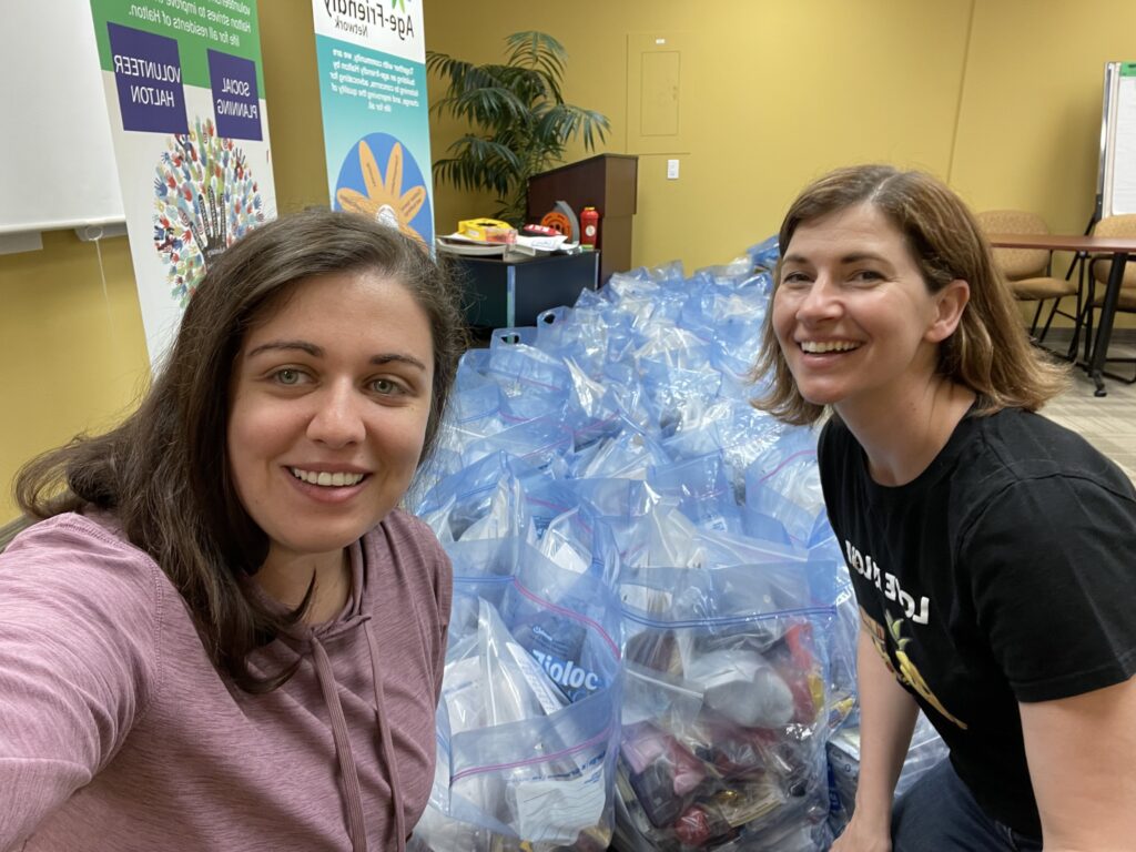 Two employees at a volunteer day with gift bags in the background