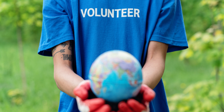 Individual with volunteer shirt holding out a globe
